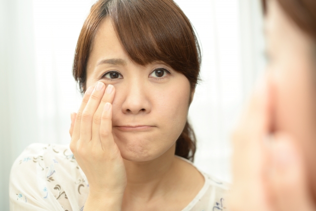 目元を触って鏡を見ている女性