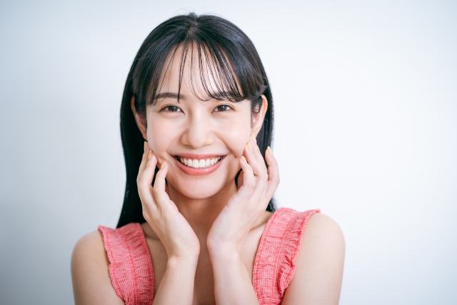 笑顔で顔を触っている女性